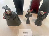 Three Nightmare Before Christmas vampire figurines alongside two black coffin-shaped boxes with red-internal cushioning shown on a white surface.