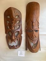 Two wooden African masks side by side on a white background, showing full front view of each mask.