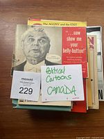 Stack of vintage books with visible front covers and some titles related to Canadian political cartoons, with a note reading 'Political Cartoons Canada'