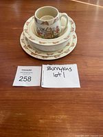 Stacked view of Bunnykins plate, bowl, mug, and egg holder showing borders and size proportions