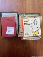 Top view of eight vintage children's books stacked, showing titles including Aesop's Fables, Miffy in the Hospital, Sesame Street, and others.