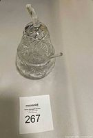 Clear lead crystal jar shaped like a pear with a glass stem top and a matching glass spoon inserted.