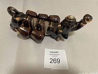 Side view of the vintage Japan MCM dachshund ceramic decanter with five attached cups shown in dark brown glaze, missing one cup.