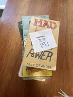 Stack of vintage paperback comic books including 'Mad Book of Word Power' on top with visible wear and age signs.