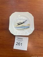Photo of one vintage ceramic plate with painted RCAF Trenton plane illustration on wooden surface with auction tag