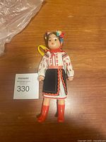 Full-body view of vintage Russian doll in traditional folk costume standing upright on a wooden surface.