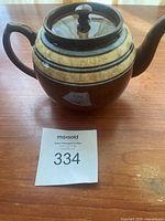 Brown Sadler ceramic teapot with cream band and dark brown stripes on wooden surface alongside auction lot number.