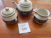 Photo showing the teapot, creamer, and sugar bowl arranged on a wooden table with an auction card number 340 visible.