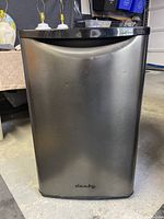 Front view of Danby bar fridge with stainless steel door and visible dents.