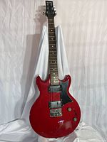Full front view of red Ibanez GIO electric guitar against white drape