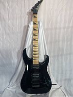 Full front view of Jackson guitar showing black body, maple fretboard and overall condition