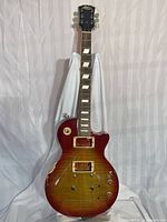 Full front view of Stagg electric guitar showing cherry sunburst finish, neck and damaged body with missing pickups and some knobs.