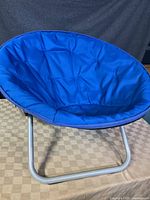Front view of the blue padded folding bucket chair with silver metal frame, sized for a child.