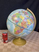 Front view of the globe showing Africa, Europe, and parts of Asia on a beige metal stand with a Coca-Cola can for scale.