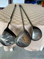 Three golf drivers laid out horizontally showing clubheads with visible branding TaylorMade Burner, Cleveland Hibore XLS, Ping G5 Titanium.