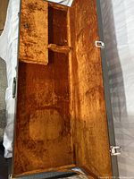 Open view of the interior lined with rust-colored plush fabric and small internal compartment with lock.