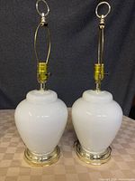 Front view showing two white glass lamps with brass bases and fittings together on a surface