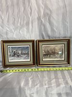 Two framed winter scene prints placed side by side with measuring tape showing approximately 14 inches wide each.