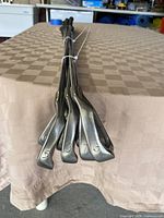 Grouped view of club heads showing irons numbered 5 through 9 laid on table