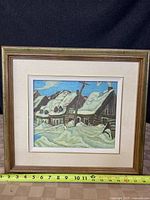 Framed canvas print showing snow-covered houses under blue sky, ruler below measuring frame size