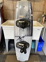 Top view of the wakeboard showing footstraps and the surface graphics in gray and white with circular designs.