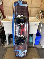 Full view of the Hobie wakeboard standing vertically showing the board's design and attached bindings.