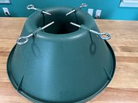 Photo of the Holiday Time green plastic Christmas tree stand showing its round base with four metal screws for securing a tree.