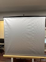 Full view of beige projector screen surface pulled down, showing minor wrinkling and creases.