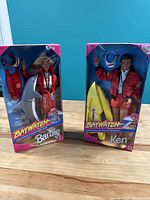 Front view of both Barbie and Ken Baywatch dolls in original packaging with accessories visible