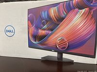 Image of the Dell monitor box showing front view with vibrant screen graphics and Dell logo.