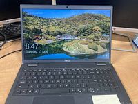 Front view of laptop powered on showing Windows 11 lock screen, keyboard and trackpad