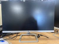 Front view of the HP 24" monitor showing the screen off, with silver base stand visible, black bezel, and silver accent.