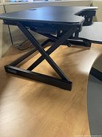 Side view showing X-crossing adjustable stand structure on wooden table surface