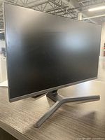 Front view of Samsung 27-inch monitor on desk, screen off, showing thin bezels and stand design.