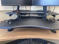 View showing front and keyboard tray of black Varidesk standing desk with dual monitor area on top.