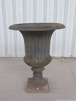 Full view of entire cast iron urn on concrete surface