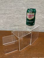 Three clear acrylic risers in stepped arrangement with soda can for scale