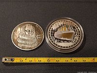 Both coins front view beside tape for scale