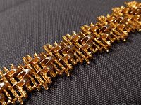 Close-up of bracelet links showing gold-tone finish and textured design
