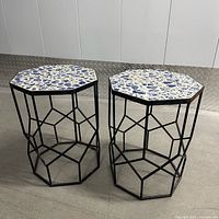 Full view of both mosaic top metal plant stands against wall