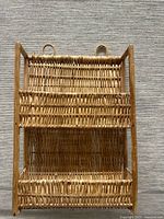 Front view of woven rattan wall rack showing two pockets and hanging loops