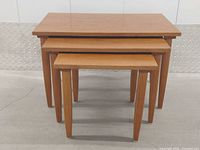 Three teak nesting tables front view stacked