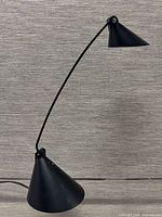 Full view of black metal desk lamp showing conical base, curved arm and shade