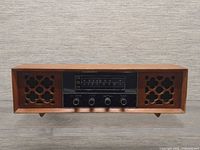 Front view showing entire wood radio, speaker grilles, dial and knobs
