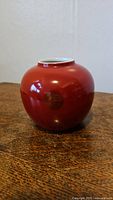 Photo of red round porcelain vase showing smooth shiny surface.