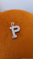 Front view of the sterling silver cubic zirconia letter P pendant placed on an orange fabric background.