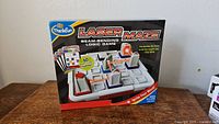 Front box of the ThinkFun Laser Maze Beam-Bending Logic Game showing game image and 60 challenge cards