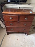 Front view of the wooden antique dresser showing four drawers and brass pulls.
