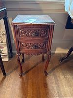 Front view of antique solid wood side table showing intricate carvings on two drawers and cabriole legs.