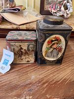 Pair of antique tea tins showing front view of detailed vintage portraits and designs on each tin.